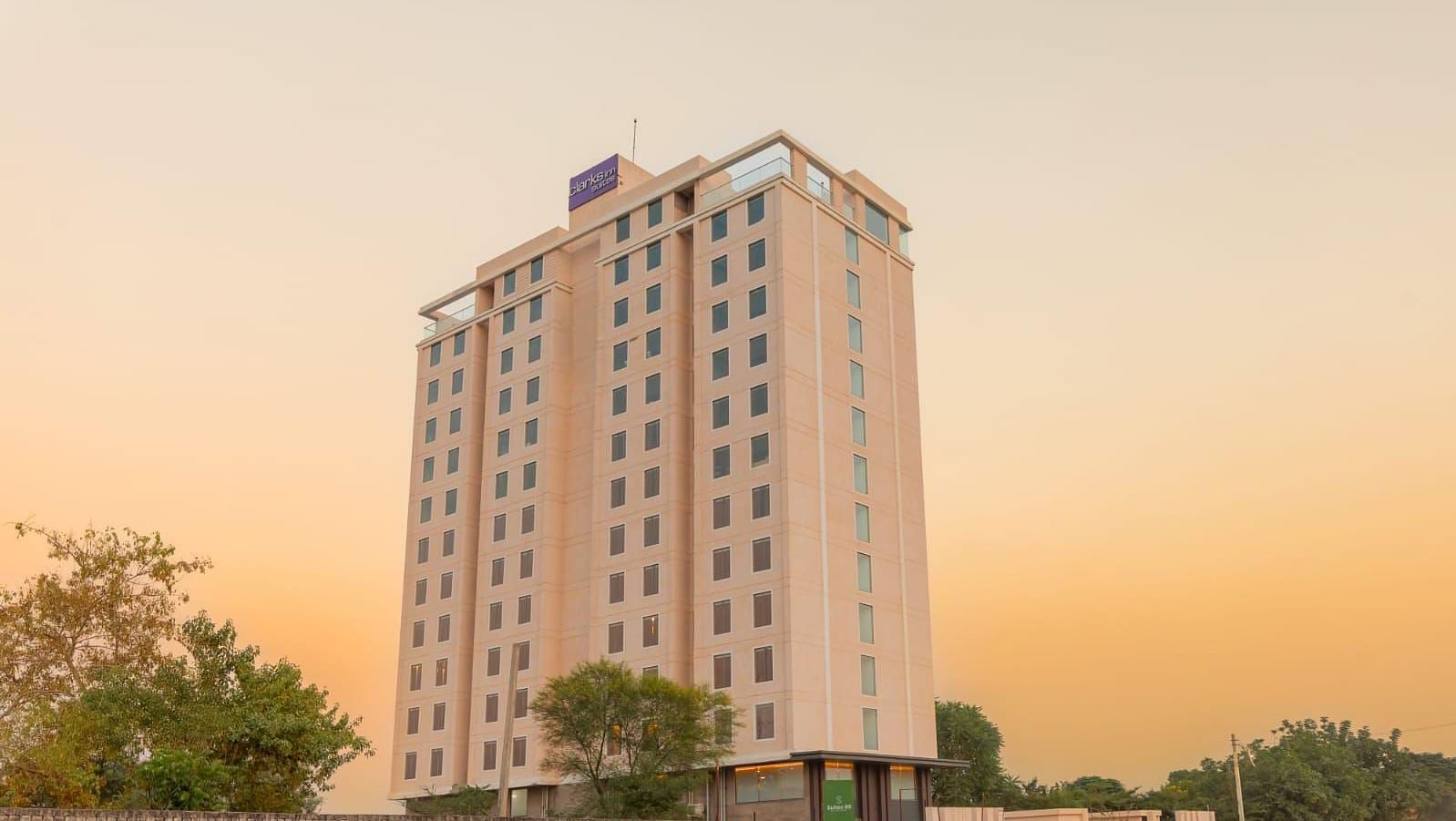 Exterior view of Clarks Inn Suites Jaipur on Ajmer Road, showcasing its elegant facade against a serene evening sky