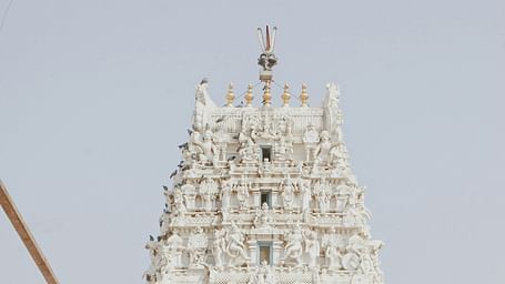 Facade image of a white temple with intricate carvings of deities on it