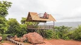 A wooden gazebo on a rocky hill overlooking a body of water.