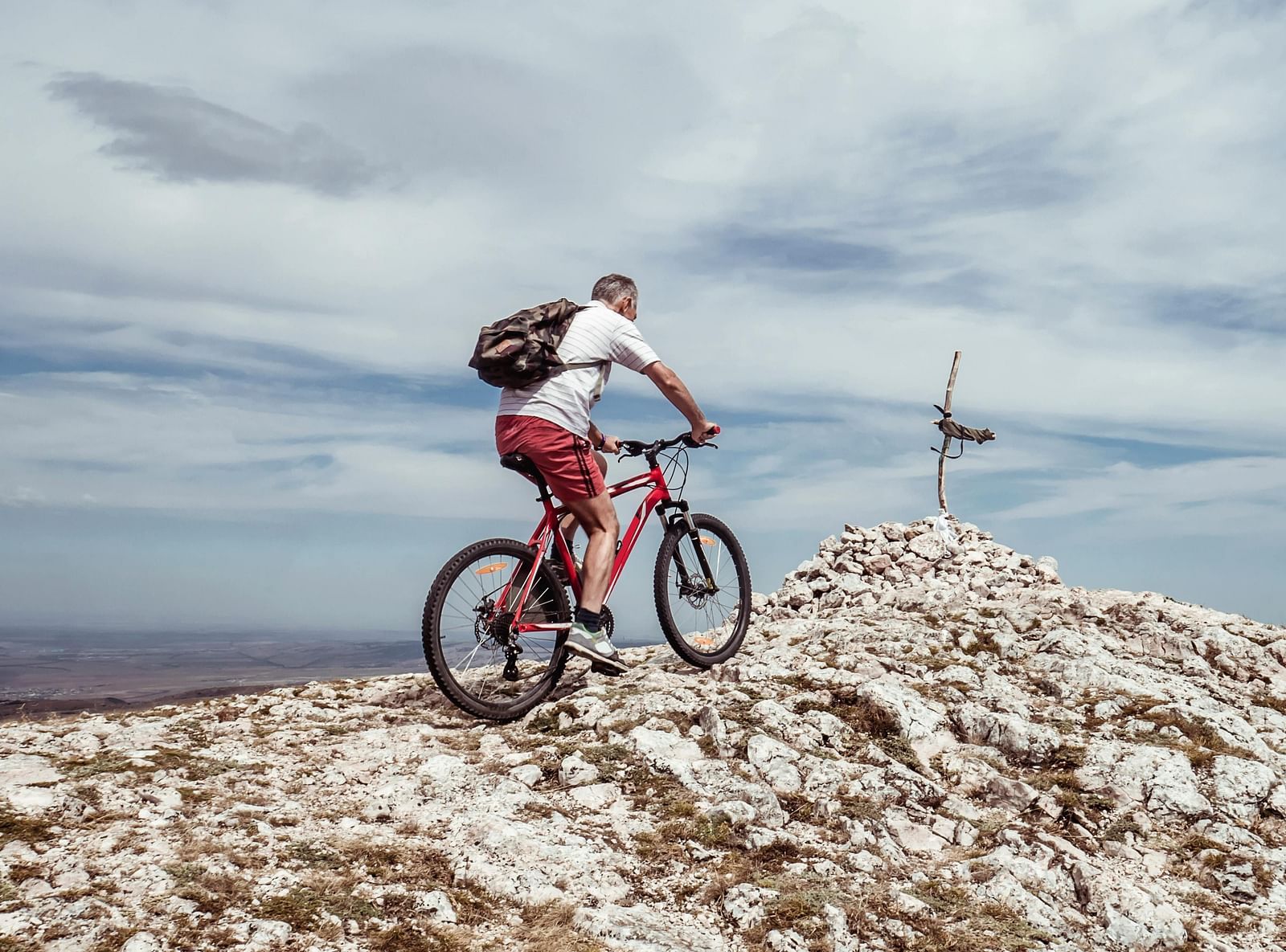 Cyclist riding on rocky terrain under a dramatic sky.