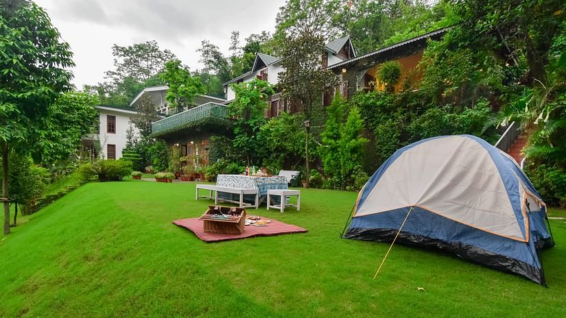 A tent pitched on a lush green lawn with a picnic blanket.