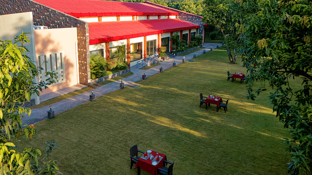Resort building with a red roof surrounded by trees and green lawns.