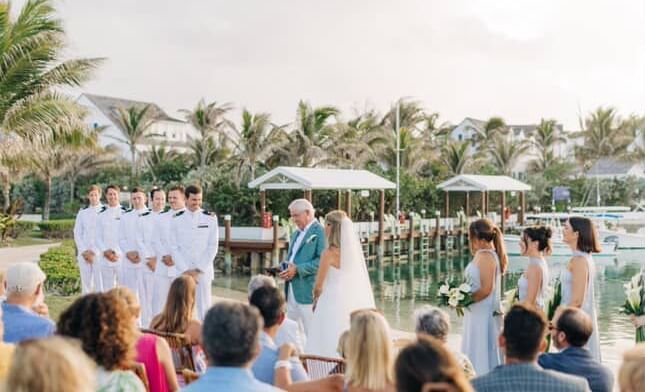 Outdoor wedding ceremony in progress with guests seated facing the couple and officiant, palm trees in the background at Abaco Inn.