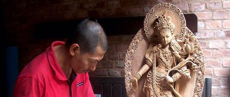 An overview of a man sculpting an idol from wood with accurate hits of the hammer.