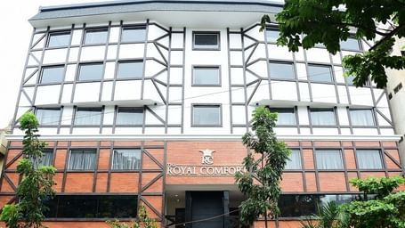 The modern, geometric-patterned exterior facade of The Royal Comfort hotel building, with orange and white panelling and a large, dark window.