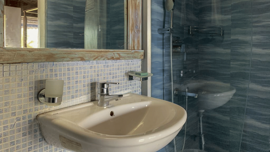 Bathroom with a white washbasin, tiled walls and a glass-enclosed shower area.