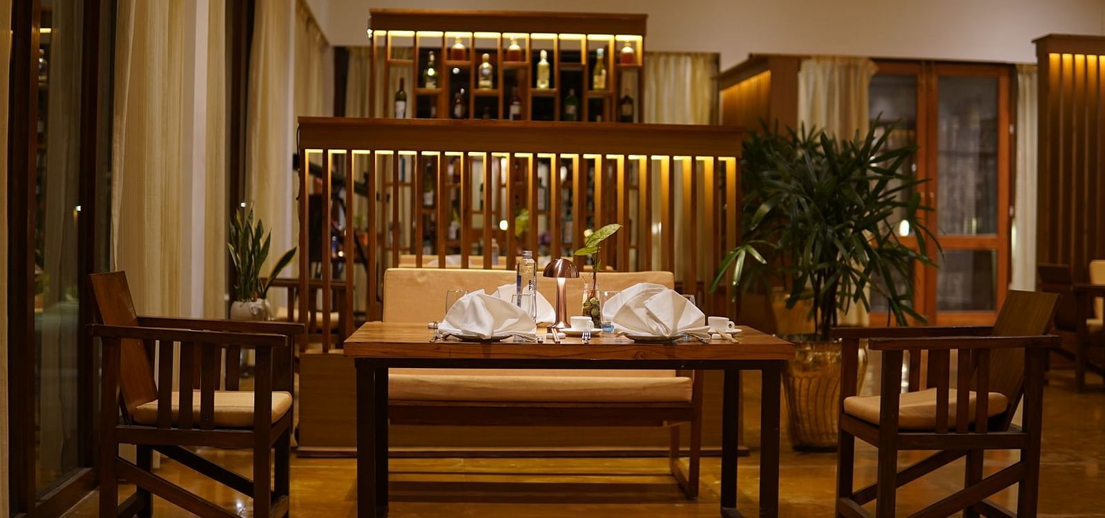 Seating arrangement at Asian Table at Saraca Resort & Spa Corbett with the bar counter in the backdrop
