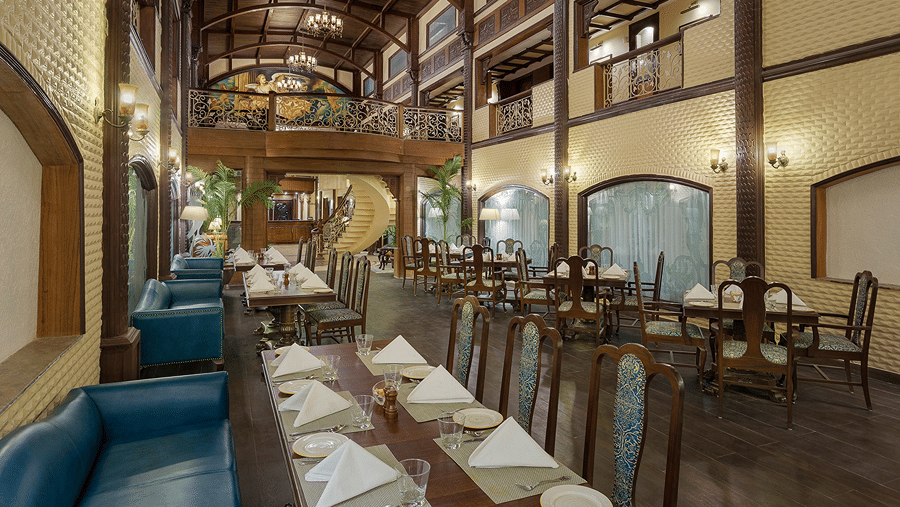 A multi-level restaurant area displaying arranged dining tables alongside wooden wall accents at Ramada by Wyndham Mussoorie Mall Road.