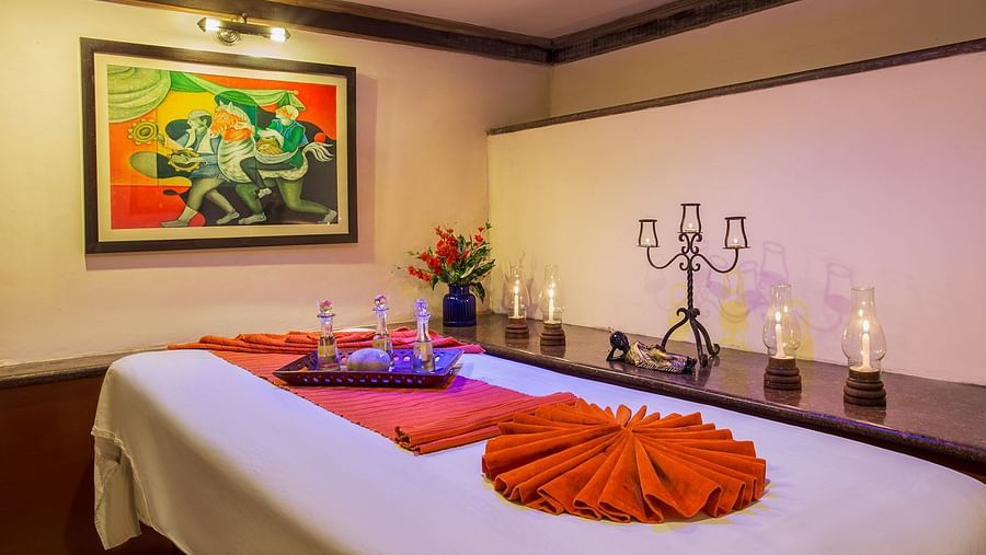 A spa table, candles beside it and a frame on the wall in a treatment room at our Spa in Nainital