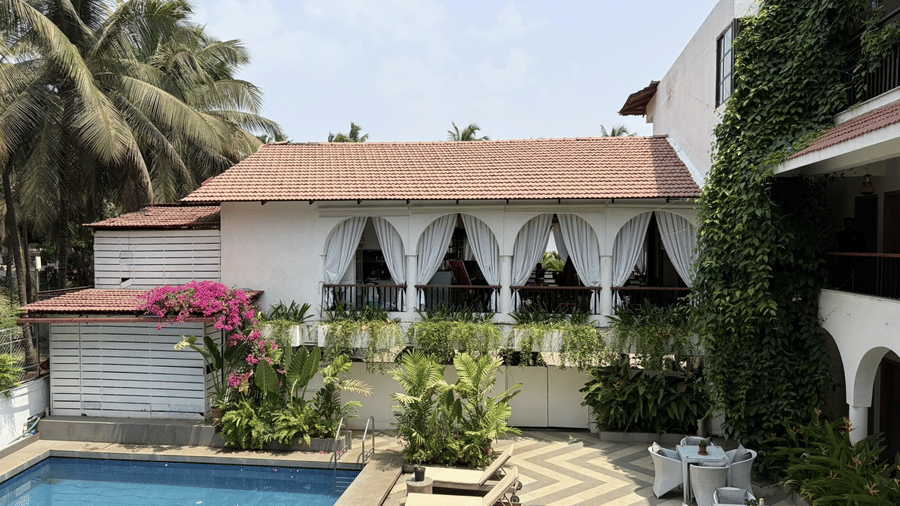 The facade view overlooking a swimming pool, sun loungers, tropical palm trees at Bougainvillea, Alibaug.