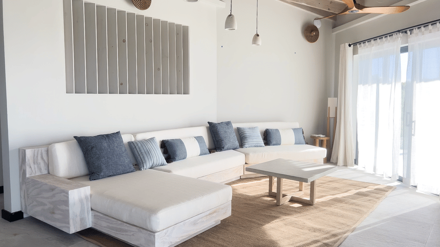 A living area with two sofas, a table, pendant lighting and a sliding glass door at Tamarind Hills Resort and Villas, Antigua.