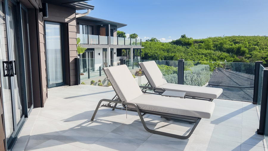 A balcony with two lounge chairs, surrounded by lush greenery at Tamarind Hills Resort and Villas, Antigua.