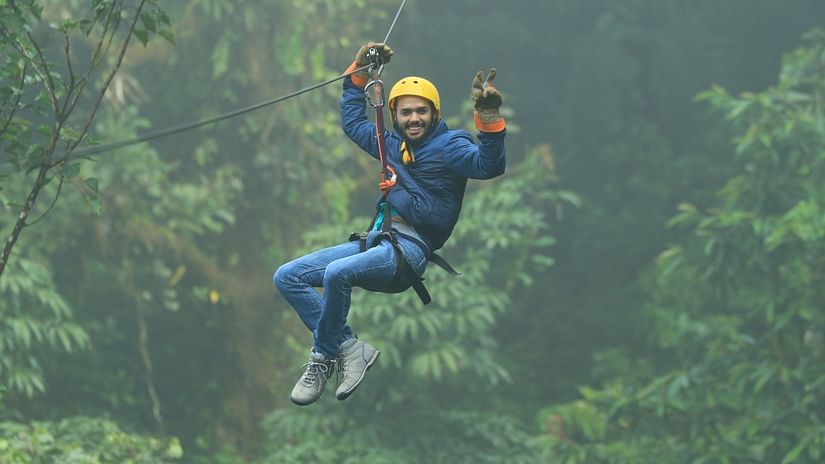 a person doing zip lining with greenery in the background - Stone Wood Jungle Resort, Dandeli
