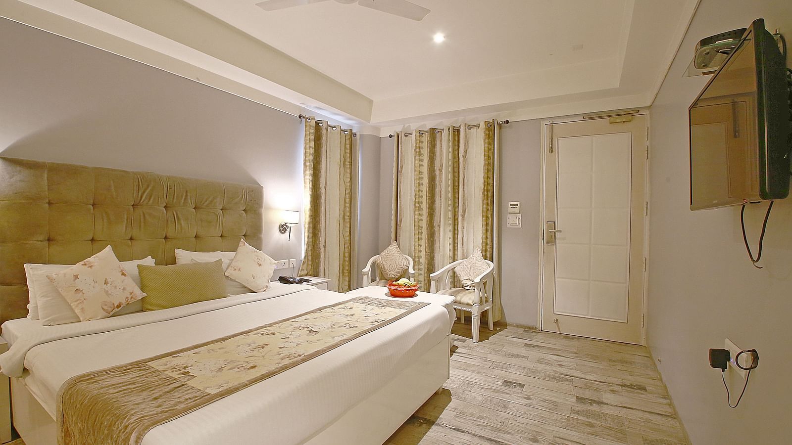 A well-lit hotel room featuring a plush double bed, sophisticated decor, and a warm ambience - Hotel Emerald, Chandigarh