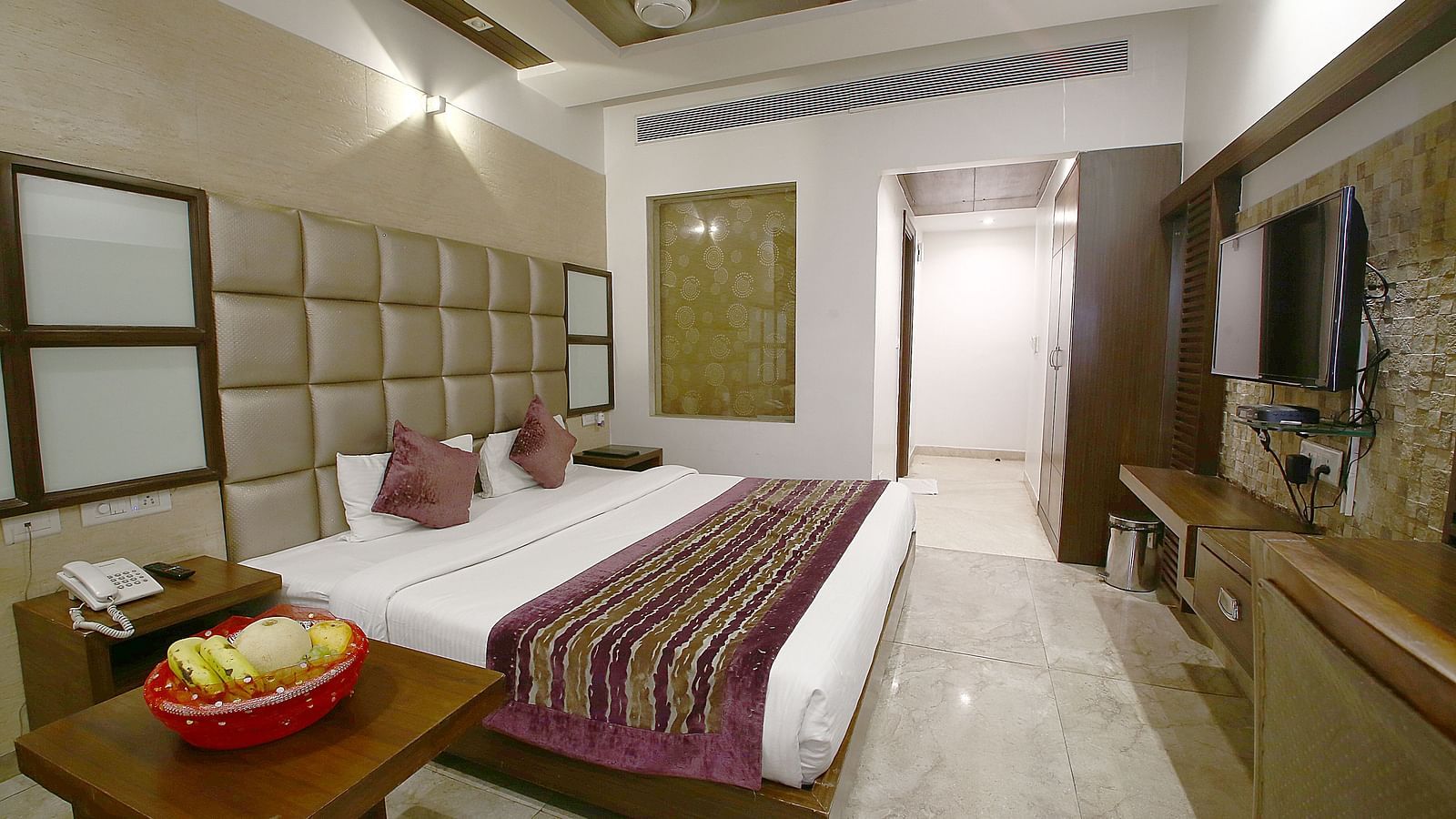 A well-appointed hotel room featuring a king size bed, decorative cushions, and modern furnishings - Hotel Emerald, Chandigarh