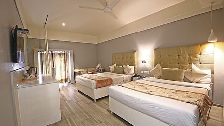 A spacious hotel room with twin beds, soft lighting, and elegant white and beige decor - Hotel Emerald, Chandigarh