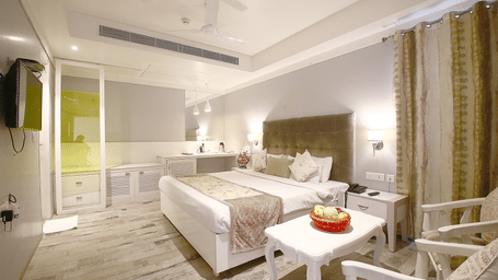 elegant air conditioned room with a double bed, bedside table, a central table with two chairs, cupboards and TV