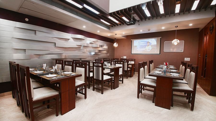 Modern dining space with various tables and chairs for guests to sit in and dine along with beautiful textured patterns on the wall and ambient  lighting - Hotel Emerald, Chandigarh