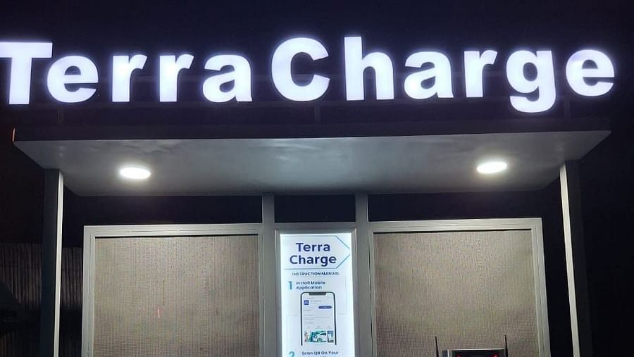 A sign displaying instructions for using an electric vehicle charging station during late evening with the terra Charger light on.