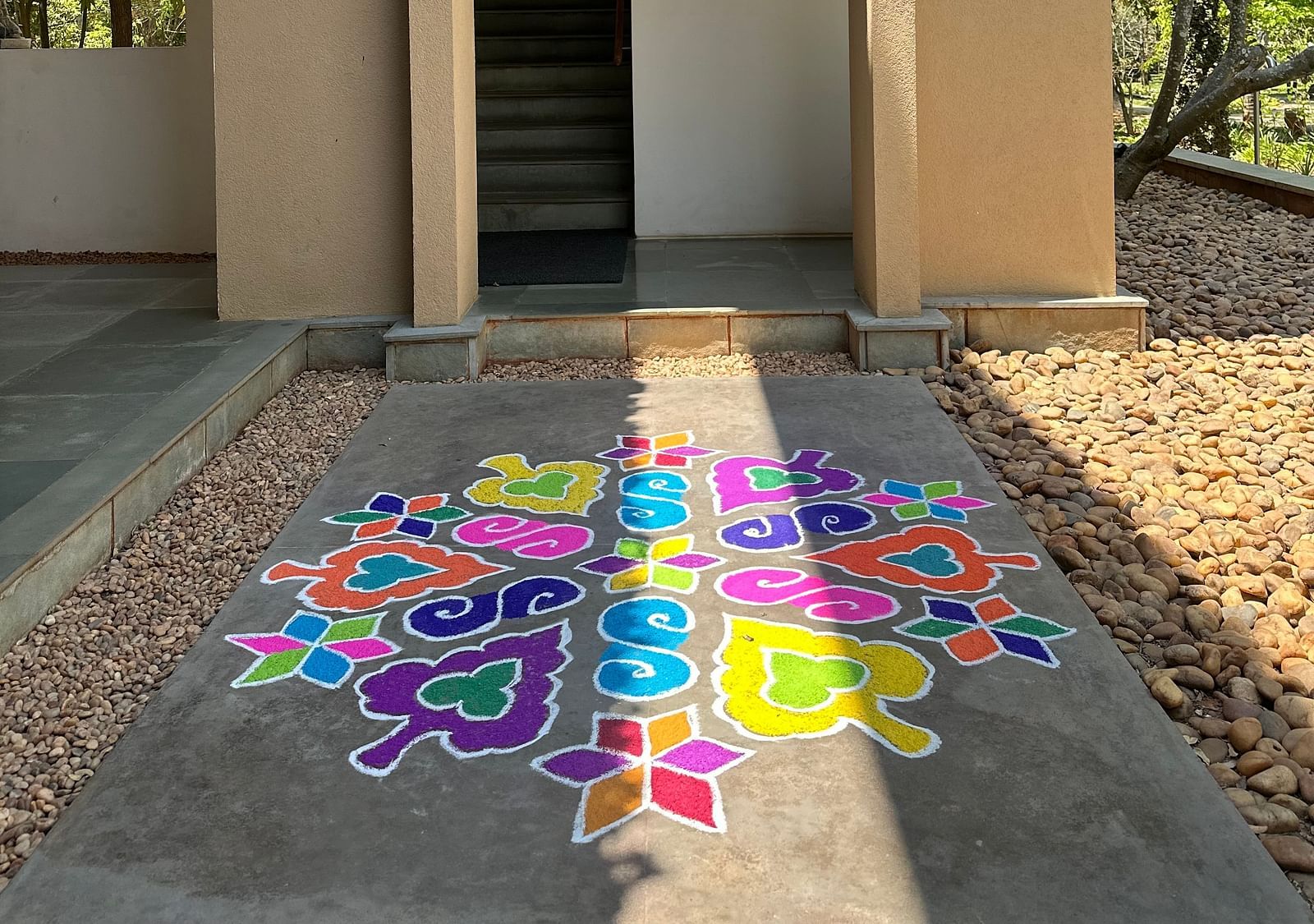 Open white door leading to garden path with colorful paint splatters, outdoor entrance, sunny day - Shreyas Retreat