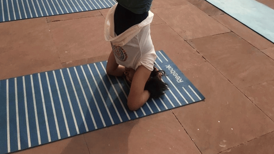 A person striking a yoga pose on a mat by the waters at Hotel Devnadi, Haridwara.