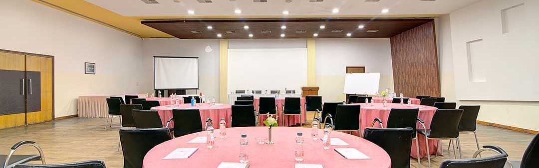 a banquet hall with cluster style seating and round tables - Camel Valley Resort, Igatpuri