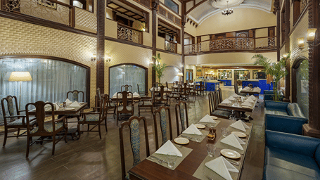 A multi-level restaurant featuring long dining tables set with place settings and chairs at Ramada by Wyndham Mussoorie Mall Road.