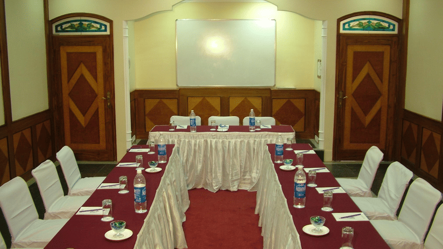 A U-shaped configuration of chairs and tables prepared for a conference meet, with notepads and packaged drinking water bottles placed on the table at Noor-Us-Sabah Palace, Bhopal.