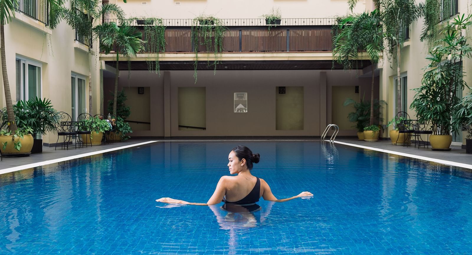 A person is floating in a swimming pool, enjoying a relaxing moment in the water | Central Mansions, Phnom Penh
