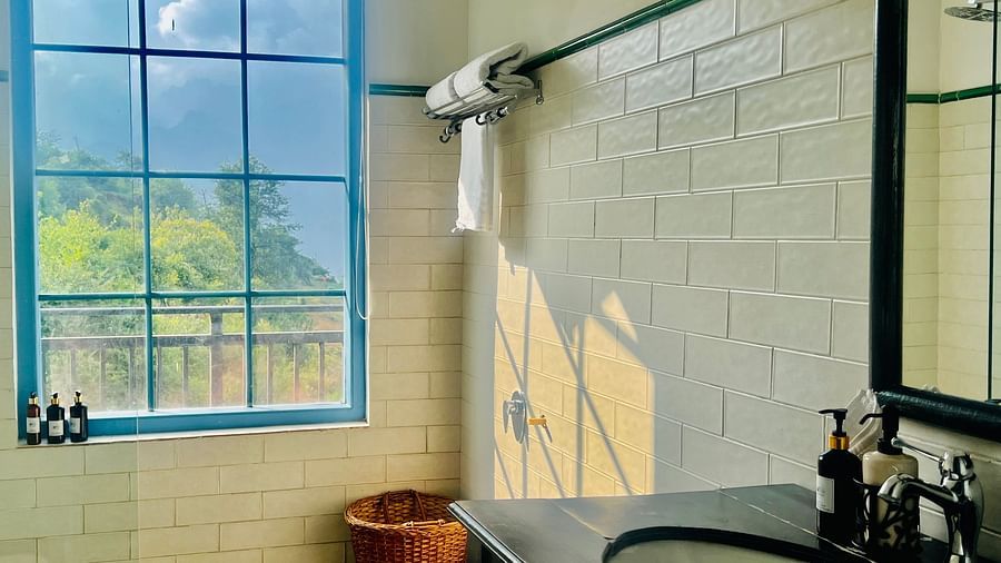 Modern hotel bathroom with large windows overlooking lush greenery, featuring a freestanding tub and minimalist decor | Faraway Cottages, Auli