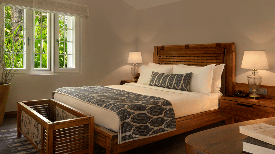 A cosy bedroom with a large bed and bright window at Amanvana Spa Resort, Coorg - Luxury Resort