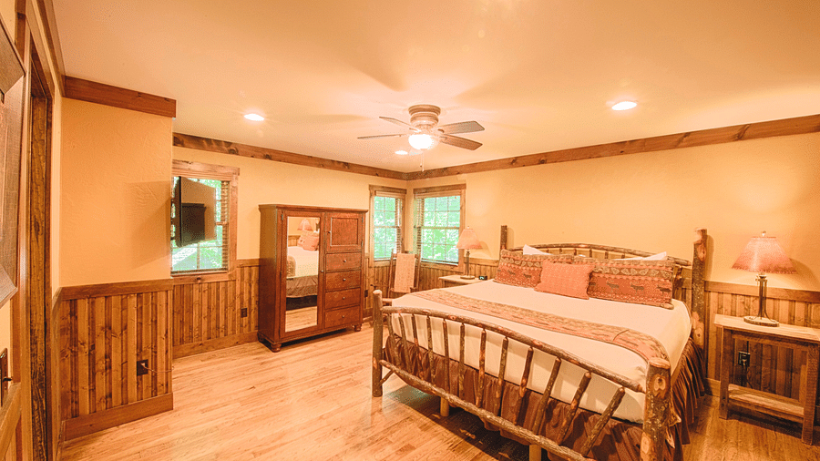 a brightly lit bedroom with a featuring a double bed along with a wooden wardrobe in the corner - Historic Tapoco Lodge