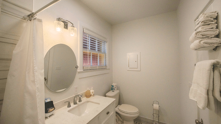 a sleek and compact bathroom with a well equipped vanity area along with a rack with fresh towels stowed on it - Historic Tapoco Lodge