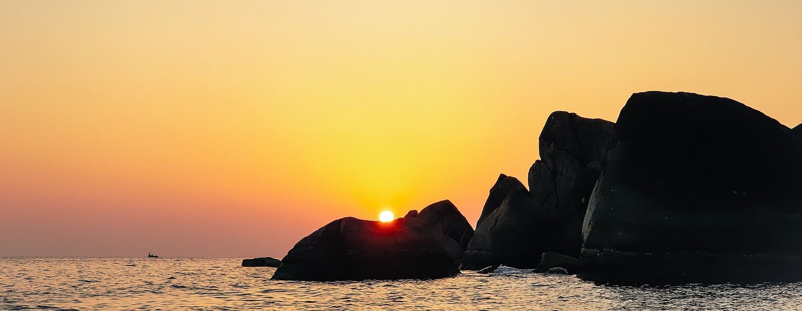 sunset near the beach with rocks in the ocean