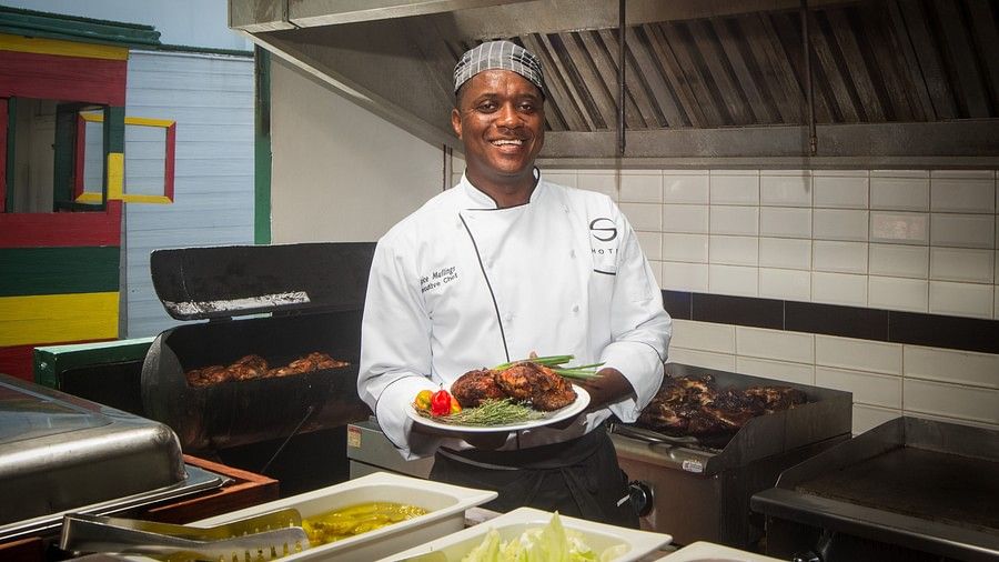A chef holding a plate of grilled food in a kitchen  - S Hotel Montego Bay, Jamaica