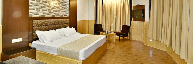 A room at DLS Hotel Devlok, Manali with a double bed, a coffee table set up and wooden flooring