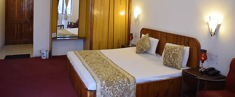 A room at DLS Hotel Devlok, Manali with a double bed and night lamps attached to the wall behind it