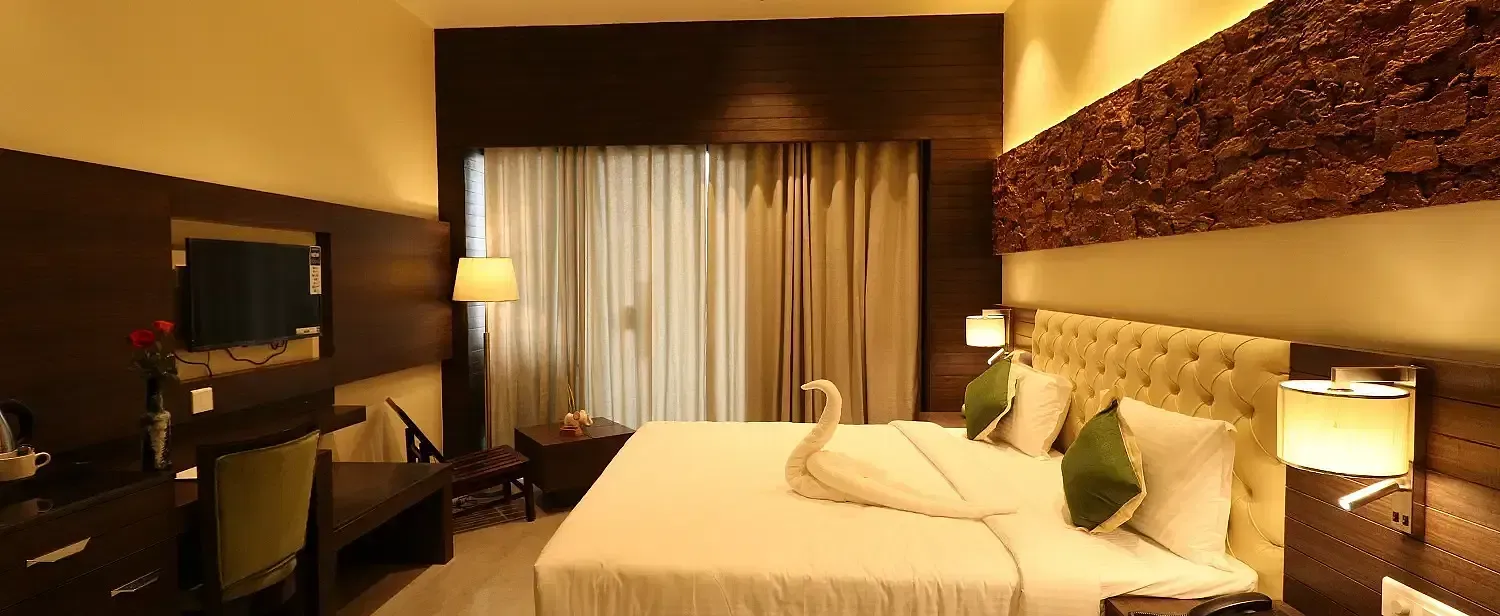 A well-appointed hotel room with a large bed, bedside lamps, and a ceiling fan, showcasing a comfortable and inviting atmosphere - Sea Hills Hotels, Sri Vijaya Puram (Port Blair)