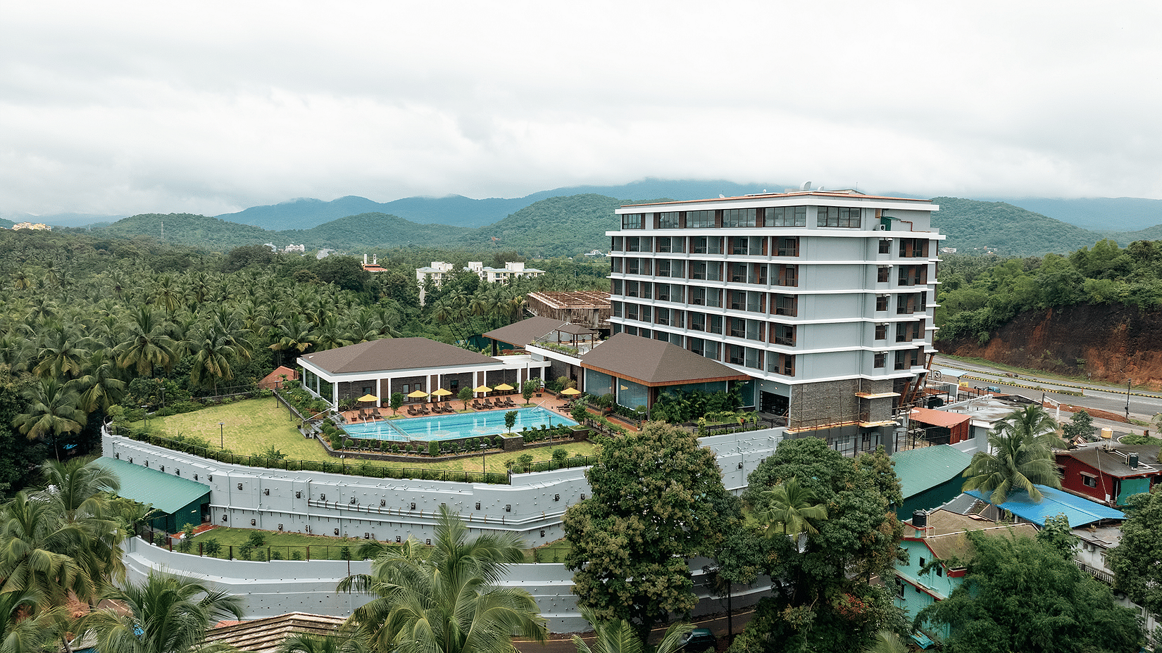 An aerial view of the facade of Cloud9 Sarovar Premiere, Palolem Goa, reveals lush trees surrounding the area, enhancing the serene and natural setting.
