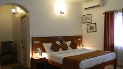 Image of Premium AC Cottage at Fantasy Golf Resort Bangalore in warm lighting featuring a double bed placed next to the window and a lamp next to the nightstand