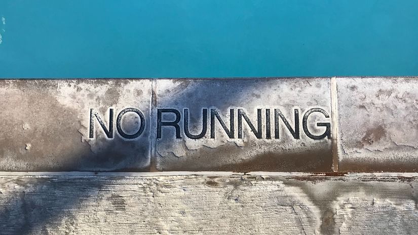 A stone slab with No Running carved into it, placed beside a swimming pool.