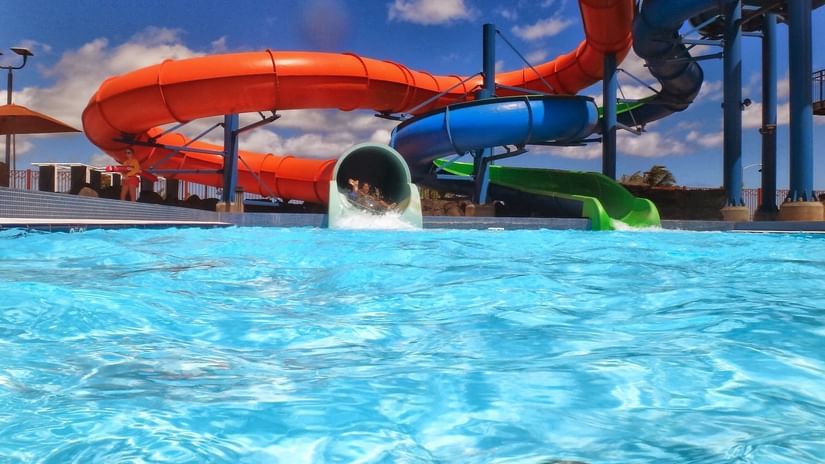 An overview of a waterslide with red and blue pipes and a waterbody at the bottom - Water Parks in Doha