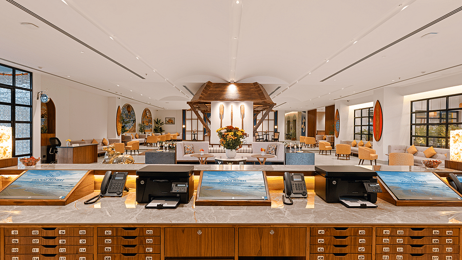 The view from the reception desk of Cloud9 Sarovar Premiere, Palolem Goa, features screens, printers, and phones, alongside wooden drawers labelled with room numbers, creating an organised and efficient workspace