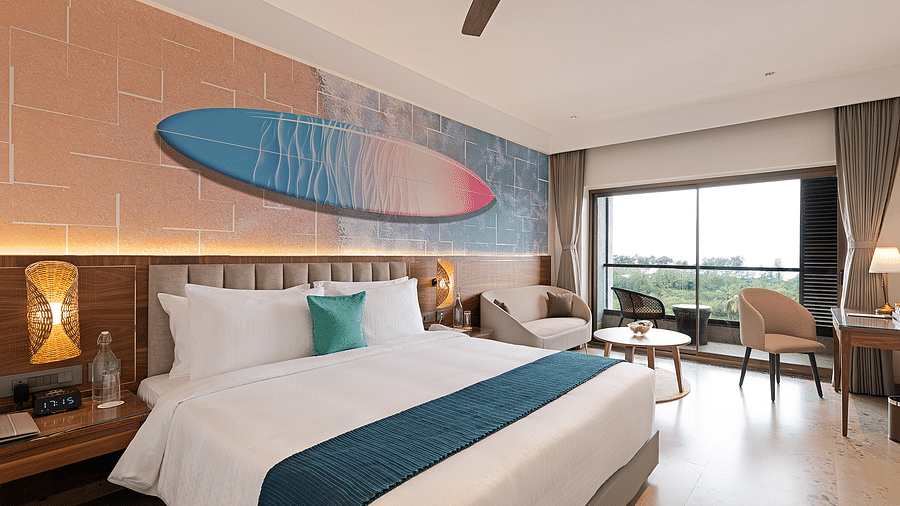 A double bed in one of the rooms at Cloud9 Sarovar Premiere, Palolem Goa, with a surfing board painting, adding coastal charm. One of the best hotels in South Goa for family stays