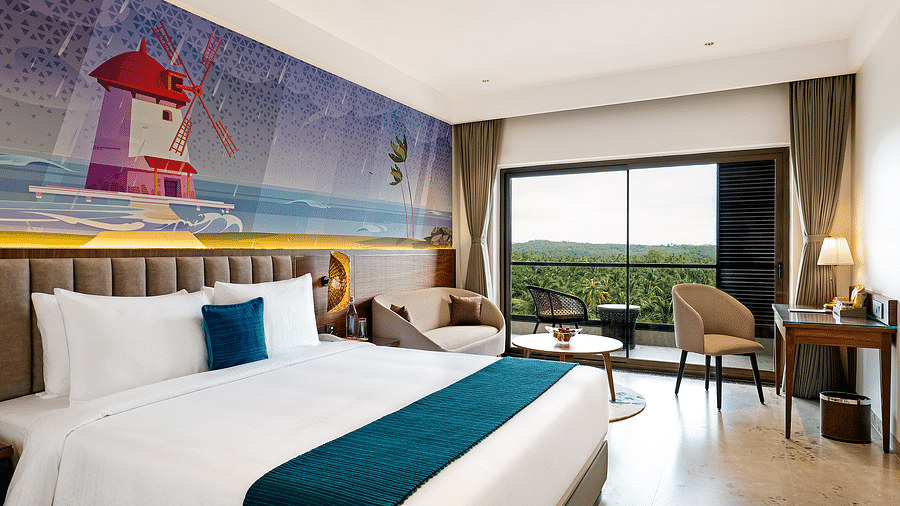 A double bed, seating, and work areas are featured in one of the rooms at Cloud9 Sarovar Premiere, Palolem Goa, with a lighthousing painting on the wall