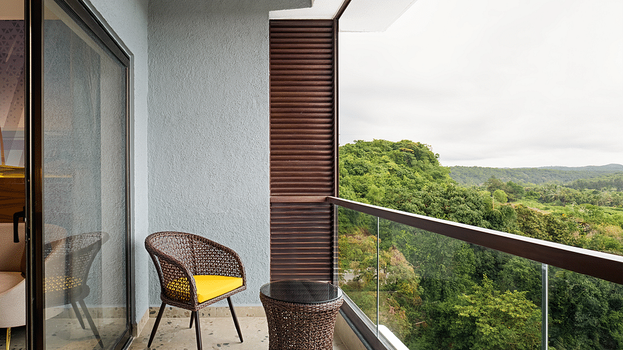 A chair and coffee table are placed on the balcony of one of the rooms at Cloud9 Sarovar Premiere, Palolem Goa, offering a perfect spot to relax