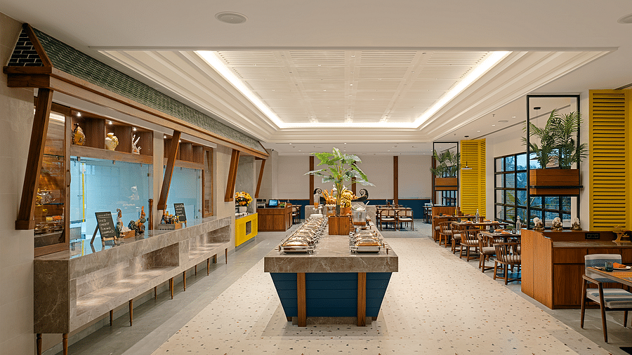 The buffet area features a central island adorned with dishes covered by silver lids, all in a brightly lit space at Cloud9 Sarovar Premiere, Palolem Goa