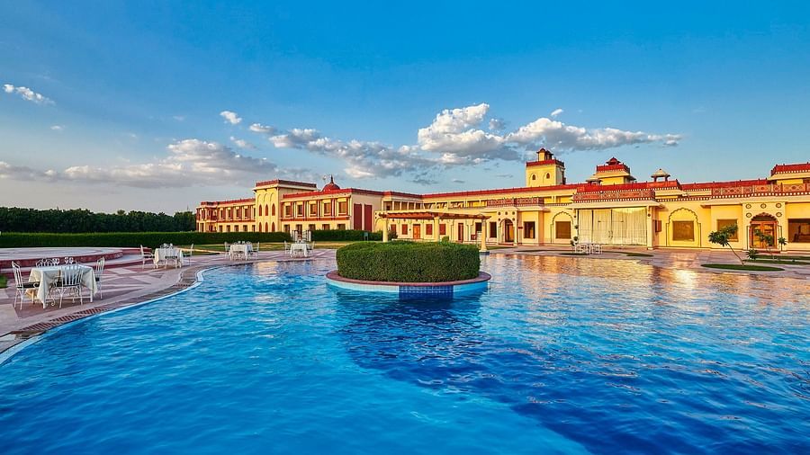 day time view of crystal blue waters in a pool with resort in the background - The Ummed Jodhpur, Palace Resort and Spa