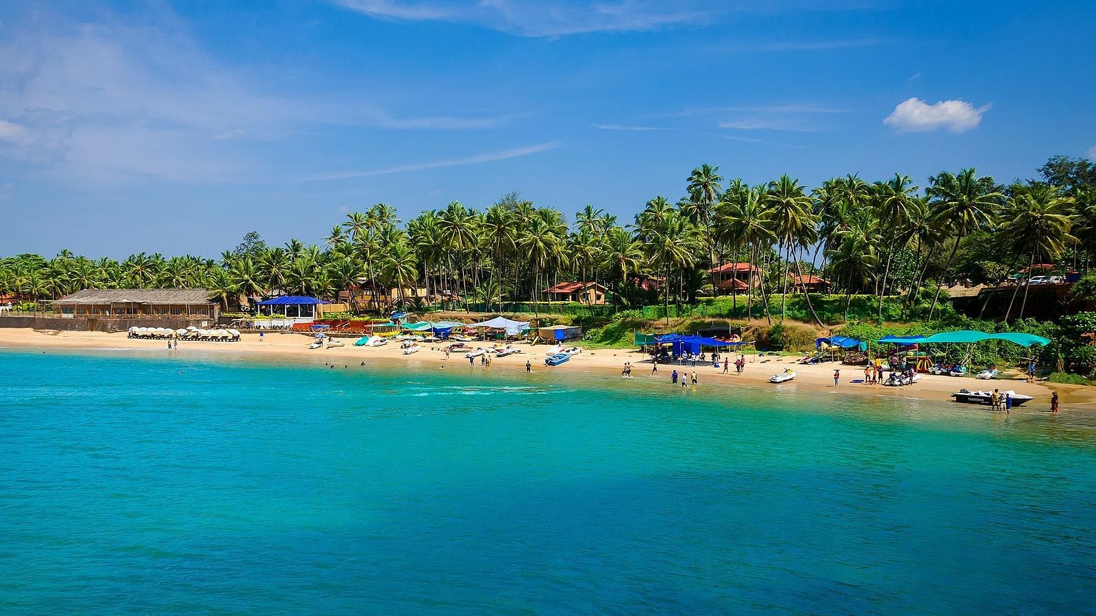 An image of a beach in goa with boats and people on the shore