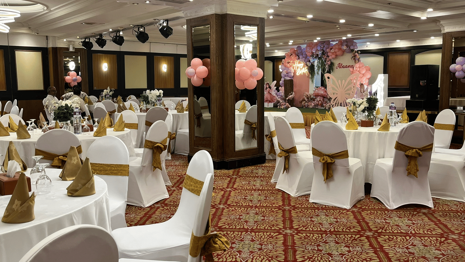 Indoor banquet hall with white chairs and round tables at Marco Polo Hotel.